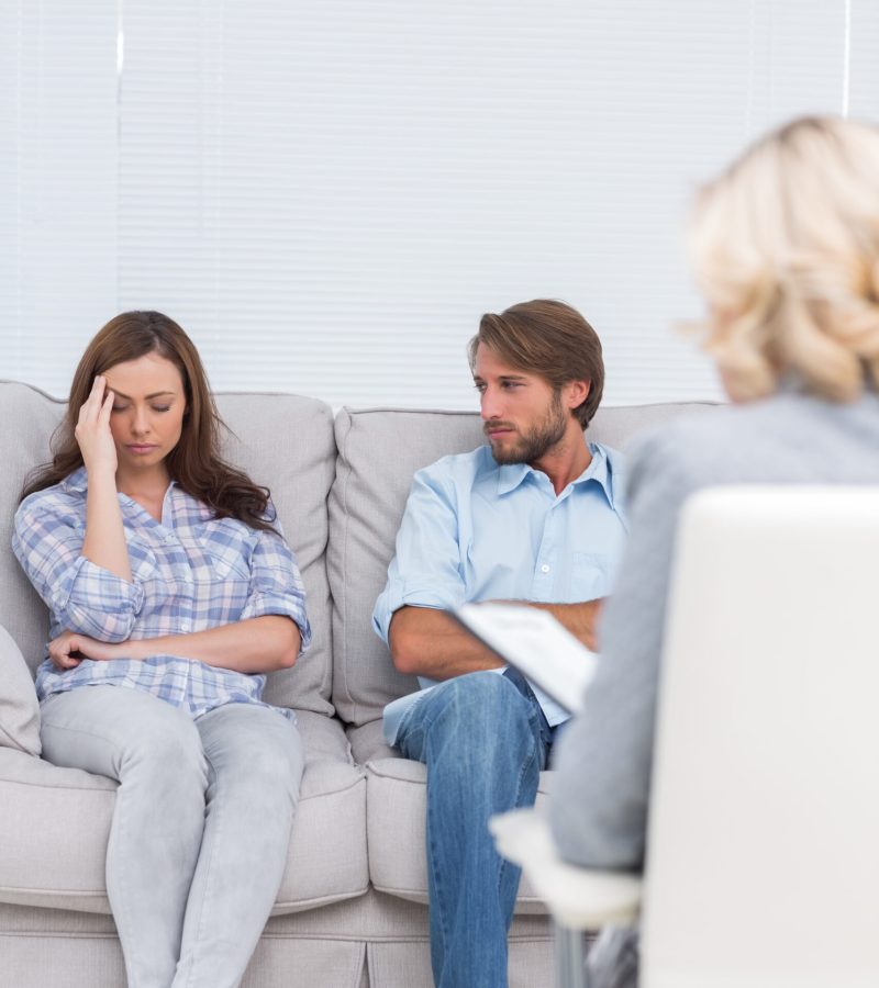 Woman crying on the couch in front of the therapist and her husband